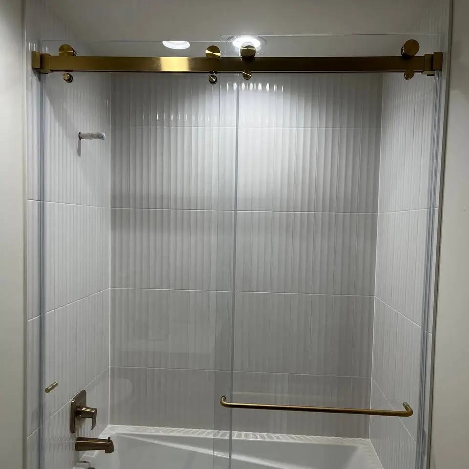 White fluted tile tub surround behind a brushed-gold sliding glass door