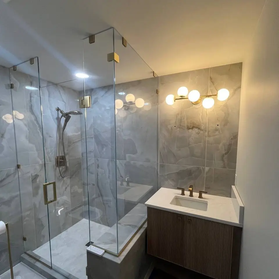 Bathroom in large onyx-look wall tile with a frameless glass shower, brass hardware and fluted vanity