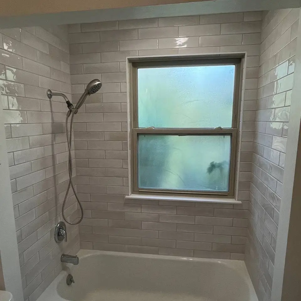 Tub surround in glossy white handmade-look subway tile with a tile-lined window return