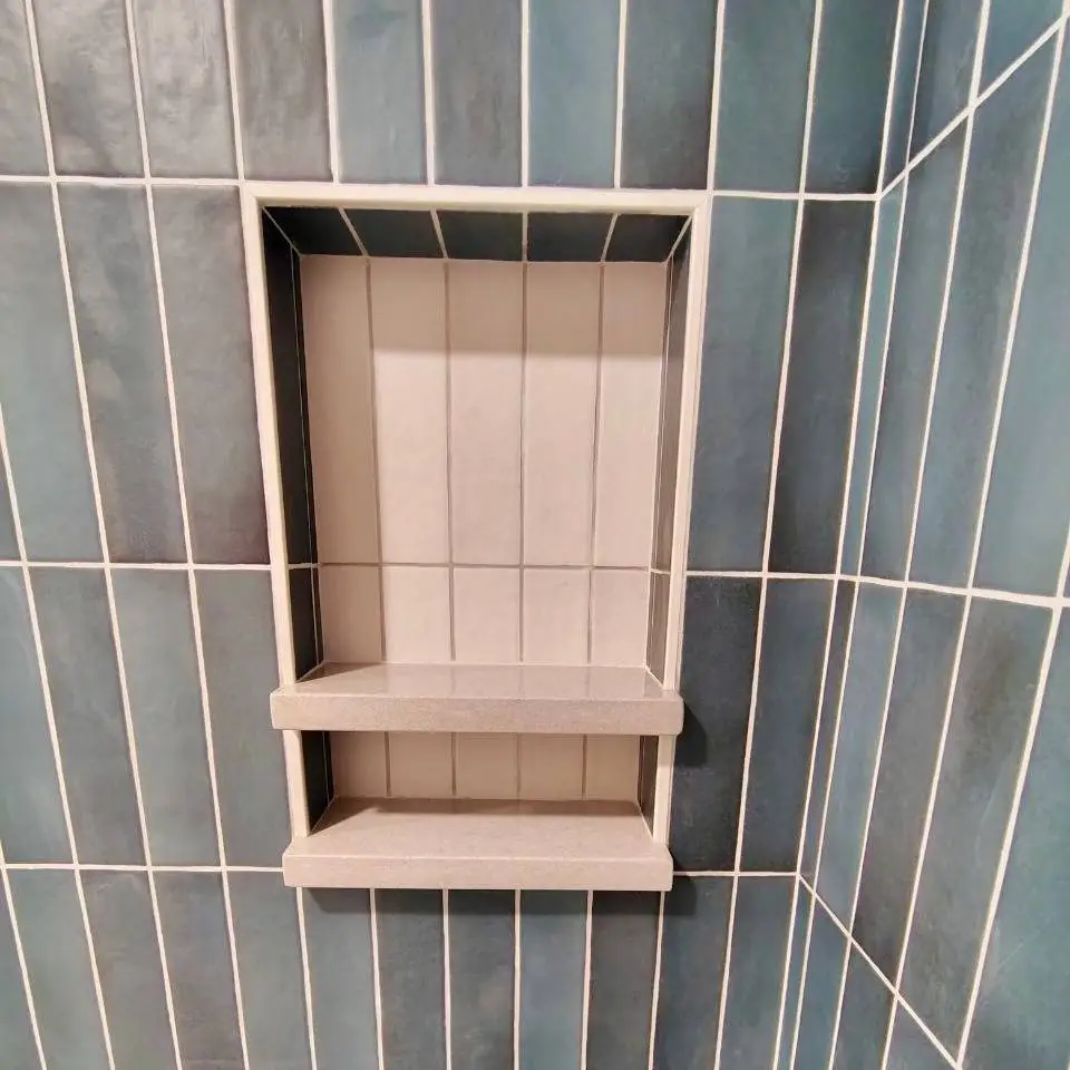 Recessed niche with two stone shelves and a cream tile back, set in teal vertical tile